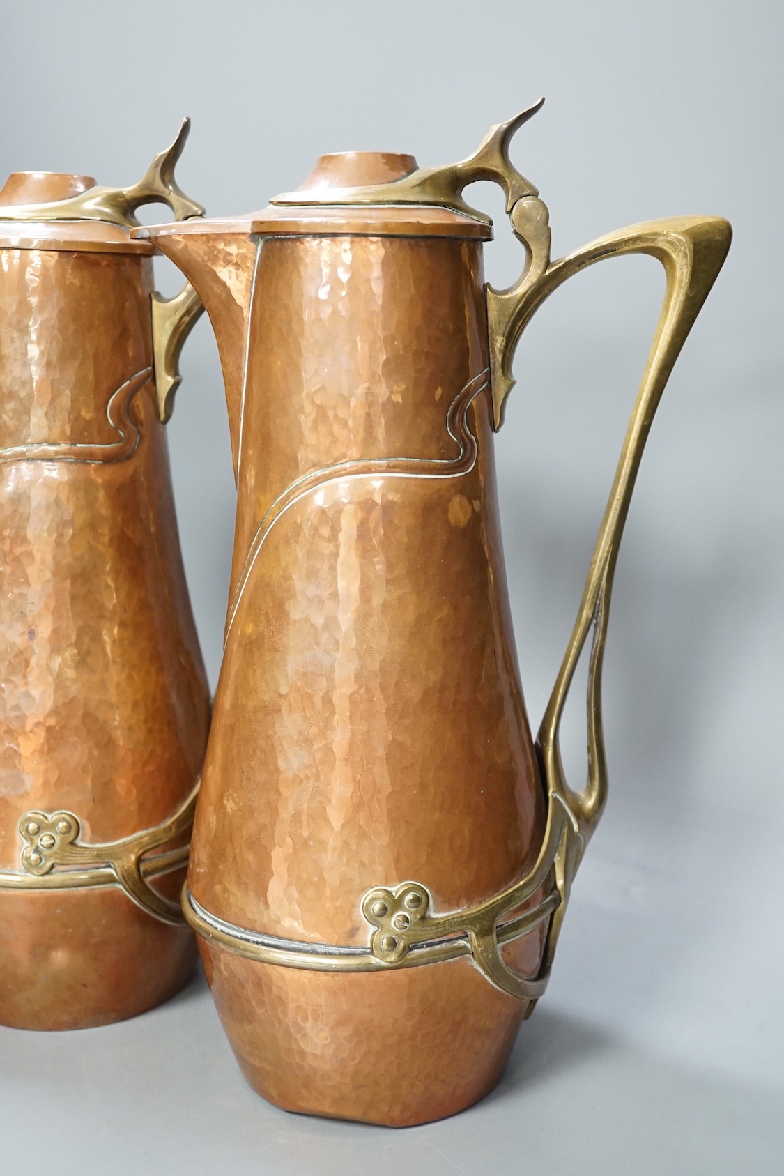 A pair of German or Austrian Jugendstil copper and brass jugs, 38cm
